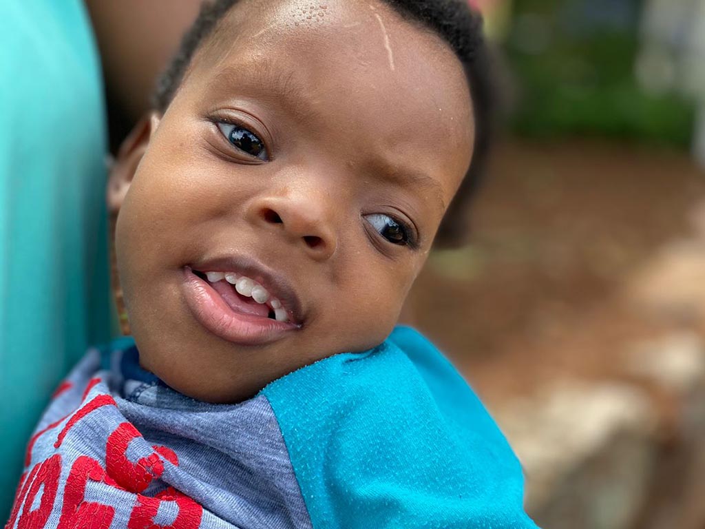 Afrikanisches Kind auf dem Arm einer Betreuerin